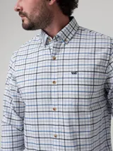 Camisa de manga larga confeccionada en franela de algodón orgánico, con diseño de cuadros en tonos blancos, azules y negros. Presenta cuello con botones, cierre frontal abotonado, bolsillo en el pecho y logo bordado.