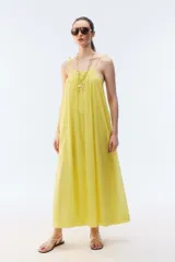 Vestido maxi solero amplio y largo de color amarillo, con escote redondo, frunces que otorgan vuelo, breteles finos ajustables con nudo en los hombros y bolsillos laterales.