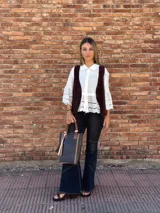 Bolso matero de cuero color chocolate con textura croco, asas cortas y detalle de costuras en los laterales. Incluye un dije con flecos en tonos beige y negro.