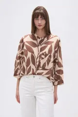 Camisa de corte holgado con estampado animal print tipo cebra en tonos negro y beige. Presenta cuello mao, cierre frontal con botones y un bolsillo aplicado en el pecho.