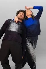 Buzo de lana merino afieltrada color negro con estampado abstracto plateado en el frente. Tiene cuello redondo y puños con forma que cubre levemente la mano. Es más largo en la parte inferior trasera.