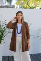 Saco abierto tipo cárdigan de punto en color chocolate, con diseño de corte recto, mangas largas y bolsillos frontales aplicados.