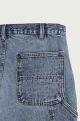 Jeans relaxed fit de tiro medio y pernera recta confeccionados en denim de algodón rígido, con diseño de carpintero que incluye bolsillos superpuestos y roturas localizadas en el frente.