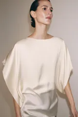 Top fluido de manga corta de Zara Woman Collection, confeccionado en hilatura de viscosa de color crudo. Cuenta con cuello barco, bajo recto y cierre en la espalda con pequeña abertura y botón.