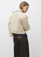 Chaqueta crop de doble botonadura color beige, con cuello pico con solapa, mangas largas y dos bolsillos laterales.