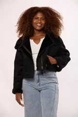 Campera corta tipo gamulán en color negro, con interior y detalles en puños y cuello de corderito sintético al tono. Presenta cierre frontal metálico y un botón decorativo en el ruedo.