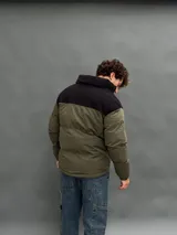 Campera puffer con capucha, diseño bicolor en verde oliva y negro, cierre frontal y bolsillos laterales.