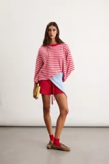 Remera oversize de algodón con diseño de rayas horizontales en tonos rosado y rojo, cuello redondo a la base y mangas 3/4.