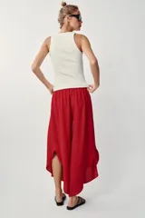 Pantalón fluido de tiro alto en color blanco, con pinzas delanteras, cintura elástica en la espalda y perneras anchas con aberturas laterales pronunciadas.