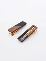 Set de dos broches para el pelo con diseño rectangular. Uno es de madera color marrón con una esquina negra, el otro es de madera color marrón con un borde negro.