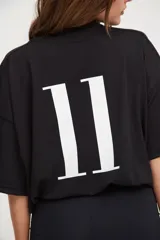 Camiseta negra de manga corta con cuello en V, corte holgado y cordón ajustable en la cintura.