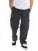 Pantalón de trekking convertible color gris oscuro, con piernas removibles mediante cierre a la altura de la rodilla, transformándolo en bermuda. Presenta múltiples bolsillos cargo con tapa y cierre, y cintura con pasadores para cinturón.