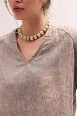Blusa de lino color lila, de corte relajado y mangas largas amplias, con escote en V y ruedo curvo.