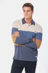 Remera polo de manga larga con diseño de bloques de color horizontales en tonos beige, azul, terracota y mostaza. Presenta cuello camisero con cierre de botones y puños elásticos.