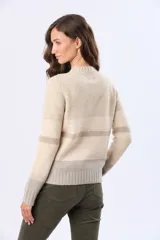 Buzo tejido de punto con diseño de rayas horizontales en tonos crema, gris y rosa. Presenta cuello redondo, mangas largas y puños acanalados, con un pequeño aplique de cuero sintético en el ruedo.
