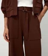 Pantalón wide leg de cintura alta en color marrón, confeccionado en modal con viscosa y elastano. Cuenta con cintura posterior elástica, cinta con hebilla para ajustar, bolsillos delanteros amplios tipo cargo y piernas rectas.