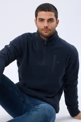 Buzo polar de abrigo en color verde oscuro, con cuello alto y medio cierre frontal. Presenta un bolsillo vertical en el pecho y bolsillos laterales, ideal para climas fríos.