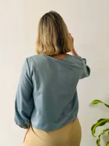 Blusa celeste con escote en V, lazo en el escote y mangas largas abullonadas con puños elásticos.