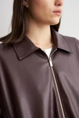 Chaqueta bomber de eco cuero en color bordó, con cierre frontal metálico y cuello clásico. Presenta un diseño de corte recto y mangas largas.