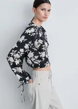 Blusa de manga larga con estampado floral en blanco y negro, cuello redondo y puños elásticos con lazos.