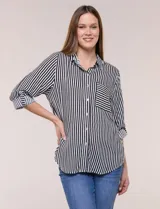 Camisa de corte clásico y silueta relajada con diseño de rayas verticales en blanco y negro. Presenta cuello camisero tradicional, cartera frontal con botones, un bolsillo aplicado en el pecho con rayas horizontales y mangas largas con sistema para arremangar.
