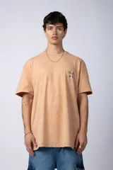 Remera de corte semi-oversize en color naranja con efecto de lavado tipo snow. Presenta un pequeño estampado gráfico en el pecho y cuello redondo.