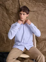 Camisa de corte clásico confeccionada en tejido Oxford de algodón, con cuello camisero, cierre frontal de botones y bolsillo en el pecho.