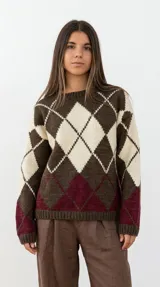 Sweater de lana merino con diseño clásico de rombos en tonos chocolate, crudo y bordeaux. Presenta cuello redondo, mangas largas y puños y ruedo acanalados.