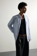 Camisa de corte regular fit confeccionada en tejido de algodón y lino, en color celeste. Presenta cuello abotonado, manga larga con puño abotonado, un bolsillo de parche en el pecho y cierre frontal con botones.