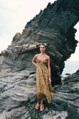Vestido midi de broderie en tonos mostaza y marrón, con escote en V, tirantes finos ajustables, abertura cut-out en la cintura y espalda con nido de abeja elástico.