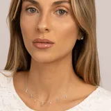 Collar plateado con cadena de eslabones y dijes colgantes: estrellas con topacios blancos, piedras redondas de topacio azul y una piedra ovalada de topacio azul en el centro.