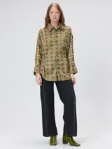 Camisa de seda con estampado geométrico de cuadrados en tonos rojizos y marrones. Presenta cuello camisero, cierre frontal con botones, bolsillo en el pecho y mangas largas con puños abotonados.