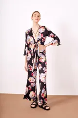 Camisa negra con estampado floral multicolor, escote en V cruzado y mangas acampanadas.