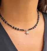 Collar tipo gargantilla compuesto por cuentas facetadas negras y cuentas plateadas pequeñas. Incluye un dije colgante de estrella plateada con incrustaciones de cristal brillante en el centro.