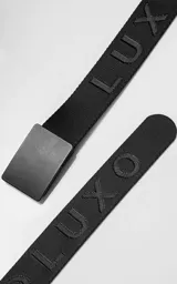 Cinturón de lona negra con hebilla metálica rectangular de color negro mate. La correa tiene la palabra "LUX" y "OK" grabada en relieve en la tela.