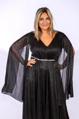 Vestido largo de fiesta en color negro con acabado brillante. Presenta un escote en V, cintura entallada con detalle de cinturón fino y mangas largas tipo capa con efecto plisado.