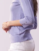 Buzo color rosa de tejido combinado con detalle de botones en las mangas y cuello redondo.