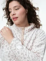 Buzo de dormir de tela fleece con estampado animal print en tonos grises y blancos. Presenta cuello alto con cierre de botones a presión y mangas largas.