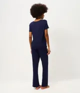 Pijama de dos piezas compuesto por una blusa de manga corta con escote redondo y un pantalón largo de corte recto con cintura elástica. La prenda presenta un bordado sutil en el pecho y un acabado liso.