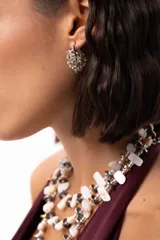 Aro tipo argolla pequeña de acero quirúrgico, decorado con una estructura de mostacillas transparentes y detalles metálicos entrelazados alrededor de toda la pieza.