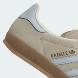 Championes Adidas Gazelle Indoor de gamuza color beige con las icónicas tres tiras en celeste claro. Presenta suela de caucho traslúcido y detalles en dorado.
