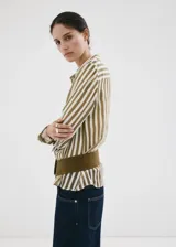 Camisa de lyocell semitransparente con estampado de rayas en tonos verde militar y blanco, cuello camisero, manga larga con puños abotonados y cierre frontal de botones.