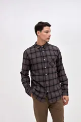 Camisa de corte regular fit, confeccionada en tela de algodón con diseño de cuadros en tonos marrones y negros. Presenta cuello clásico, cierre frontal con botones personalizados y un bolsillo en el pecho con el logo de la marca bordado.