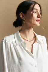 Camisa de manga larga con caída fluida, diseño de silueta suelta, cuello clásico y cierre frontal con botones.
