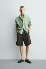 Camisa de corte relajado confeccionada en tejido fluido con mezcla de lyocell. Presenta diseño de rayas verticales, cuello solapa, manga larga con puños abotonados, bolsillos de plastrón con solapa en el pecho y cierre frontal con botones a presión.