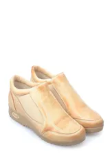 Zapato bajo de cuero color beige, con paneles elásticos laterales para un calce fácil y suela de goma dentada con logo grabado en el talón.