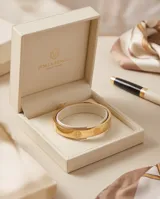 Esclava rígida de acero con baño de oro, diseño de superficie lisa con grabados circulares del símbolo de San Benito.