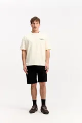 Remera boxy de color beige, de manga corta y cuello redondo, con estampa en la espalda inspirada en código de programación y estética digital.