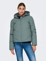 Campera acolchada de corte puffer con capucha, cierre frontal de cremallera y mangas largas con hombros caídos. Presenta un diseño repelente al agua con puños internos elásticos para mayor protección contra el viento.