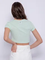 Top corto de manga corta color amarillo con estampado de lunares blancos y aberturas circulares en el escote.